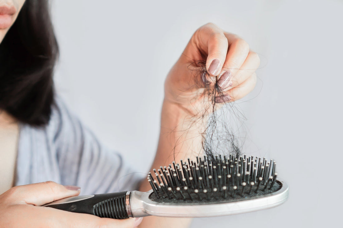 woman pulling hair out of a hair brush 